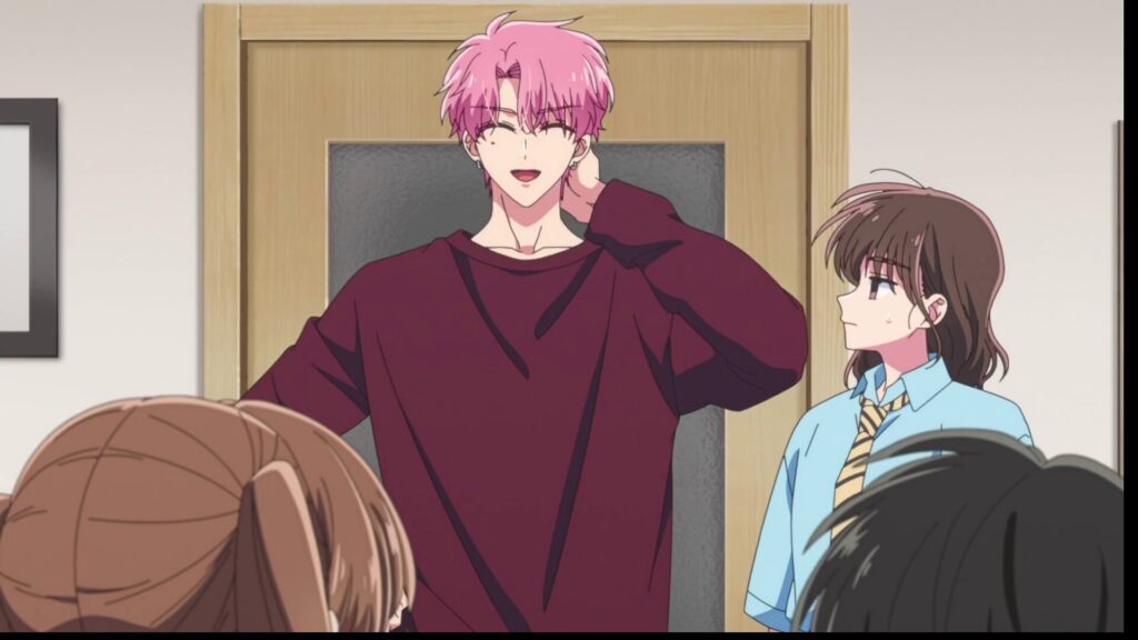 『多聞くん今どっち！？』第12話。ピンクの髪のアイドル・多聞が、照れたように首の後ろを触りながら微笑むシーン。