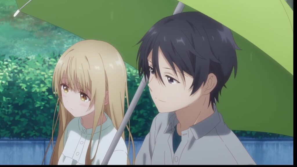 アニメ『お隣の天使様』2期・第2話より、雨の中、一本の緑色の傘に一緒に入る藤宮周と椎名真昼。周が傘を差し、隣を歩く真昼を優しく見守るような表情で並んでいるシーン。